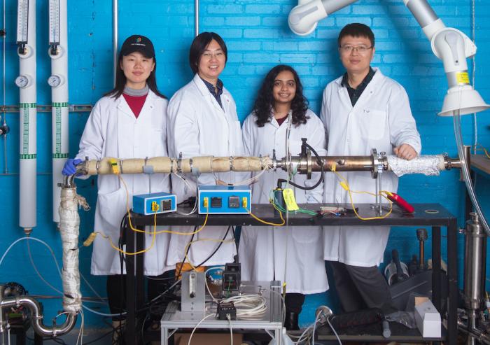 
              Left to right: Graduate student Chuwei Zhang, Assistant Professor Sili Deng, graduate student Maanasa Bhat, and postdoc Jianan Zhang stand behind the lab-scale apparatus they use to investigate a low-cost method of synthesizin...