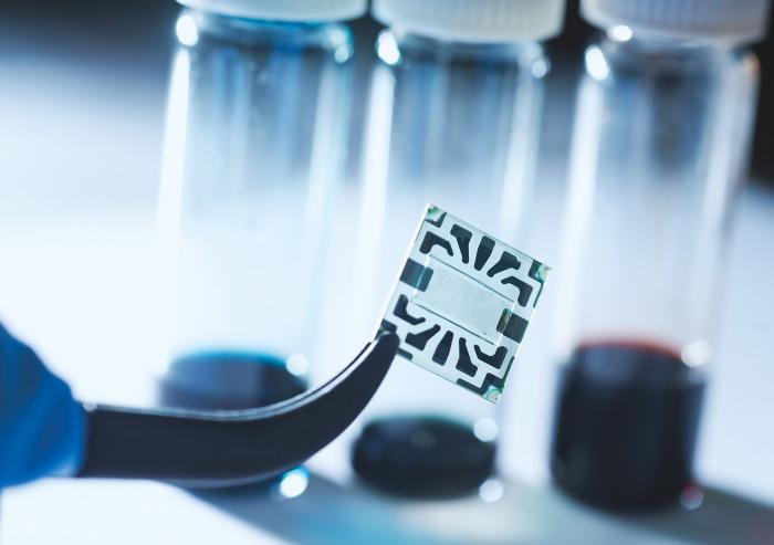 A new flexible graphene solar cell developed at MIT is seen in the transparent region at the center of this sample. Around its edges are metal contacts on which probes can be attached during tests of device performance.Photo: Stuart Darsch
