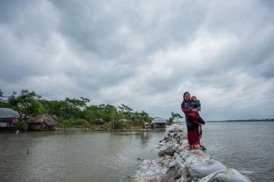For the coastal country of Bangladesh, once-in-a-century storm tides could strike every 10 years — or more often — by the end of the century, scientists report. In this photo, a Bangladeshi woman and child walk over the top of a sandbag embankment in Khulna on May 4, 2019.