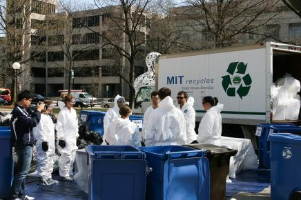 group of people sort trash from blue bins