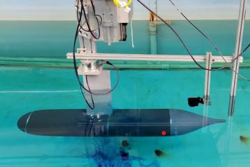 Initial experimental setup, showing the submerged axisymmetric model rigidly attached at about mid-length to the towing carriage through a streamlined strut.