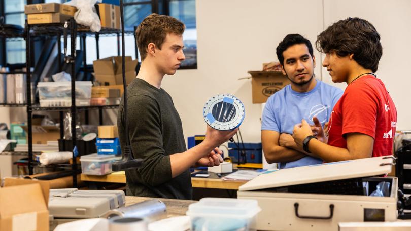 three men working at a project table in aero astro lab
