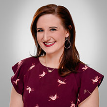 headshot of woman with brown hair and red shirt