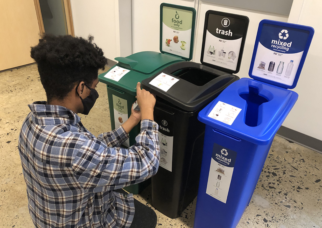 student places labels on tall narrow waste bins
