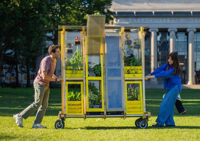 Zachary Rapaport (left) and Aleks Banaś move their farm cart across the MIT campus. The two graduate architecture students co-designed and built the cart.
