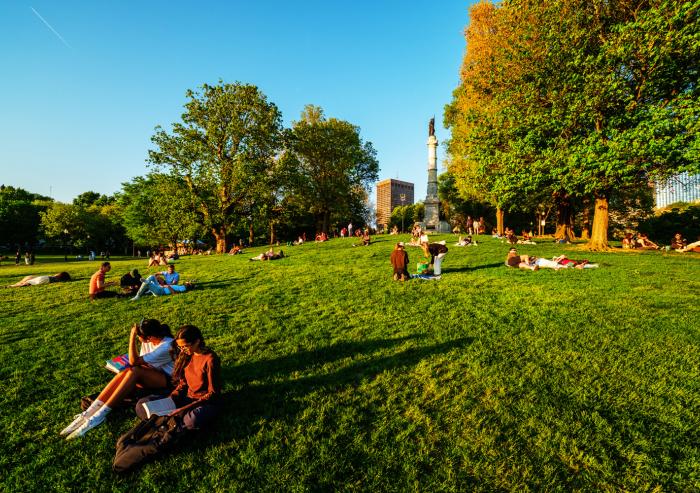 People relax on the Boston Common lawn beneath the Soldiers and Sailors Monument.