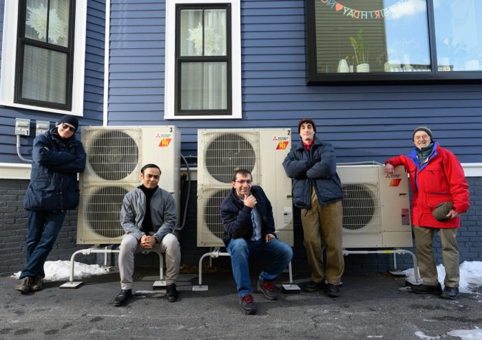 A modeling study by an MIT team has shown that electrifying residential heating can be a substantial step toward reducing carbon emissions, as well as costs, over the combined electricity and natural gas sectors. Here, the team poses beside a high-efficiency electric heat pump system that provides heating to the home, replacing the natural gas-fired furnace. Left to right: Audun Botterud, Saurabh Amin, Rahman Khorramfar, Morgan Santoni-Colvin, and Leslie Norford. Not pictured: Dharik Mallapragada.