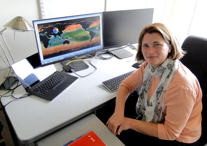 MIT research scientist Stephanie Dutkiewicz in her office with a display of her phytoplankton model simulation 