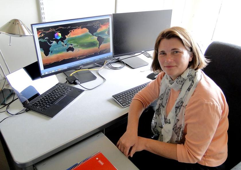 MIT research scientist Stephanie Dutkiewicz in her office with a display of her phytoplankton model simulation 