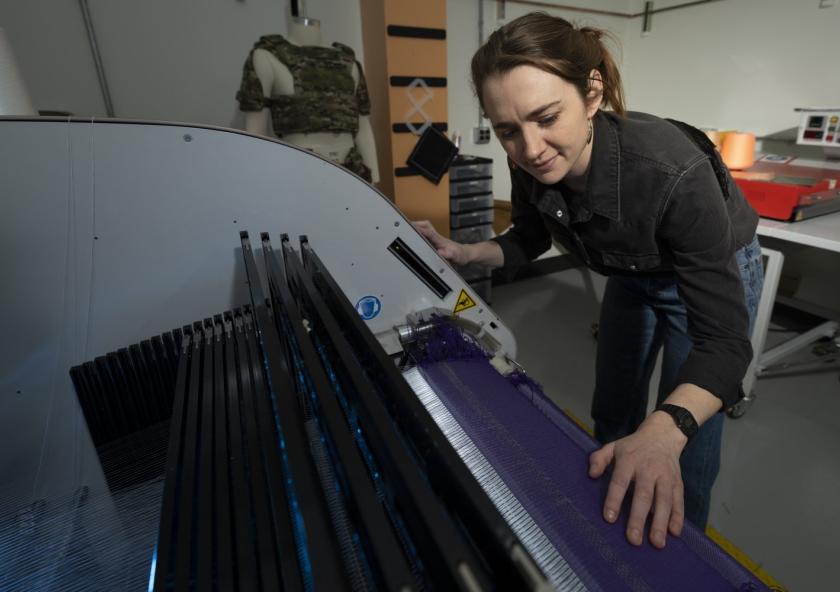 
              At Lincoln Laboratory’s Defense Fabric Discovery Center, Erin Doran demonstrates how reflective fibers can be woven into textiles. Such fibers could function as indelible, scannable labels to easily sort fabrics for recycling. 
   ...