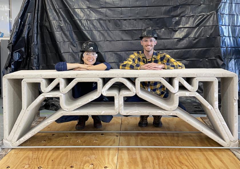MIT Department of Civil and Environmental Engineering postdoc Hajin Kim-Tackowiak (left) and graduate student Zane Schemmer pose with the 3D-printed concrete bridge they designed and load-tested.