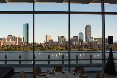 the boston skyline is seen with the charles river in foreground