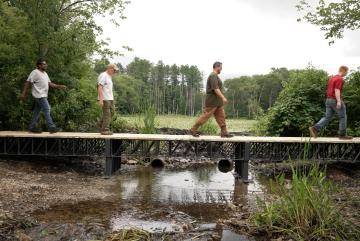 Atlas Building Composites, an MIT spinout, recently supplied the U.S. Army Corps of Engineers with American-made recycled composite trusses to construct a 40-foot bridge in a Massachusetts wetland, pictured.