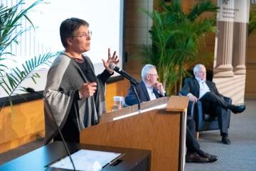 Susanne Moser, director of Susanne Moser Research and Consulting, addresses MIT’s second Symposium on Climate Change. In the background are Andrew Steer, president and CEO of the World Resources Institute, and Richard Schmalensee, the Howard W...
