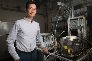 XiaoYu Wu pictured with the reactor his team used for the research. MIT researchers have developed a new system that could potentially be used for converting power plant emissions of carbon dioxide into useful fuels. The method may not only cu...