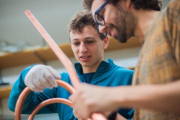
              Rising MIT sophomore Sam Packman (left) and his advisor Nicolo Riva, a postdoc at the MIT Plasma Science and Fusion Center, examine a VIPER cable, a special type of high-temperature superconducting cable that holds promise for use i...