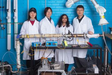 
              Left to right: Graduate student Chuwei Zhang, Assistant Professor Sili Deng, graduate student Maanasa Bhat, and postdoc Jianan Zhang stand behind the lab-scale apparatus they use to investigate a low-cost method of synthesizin...