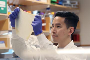 
              Biological Engineering graduate student Zijay Tang demonstrates the durability of Syn-SCOBY, a kombucha-inspired living membrane. 
              Photo: Zijay Tang
      