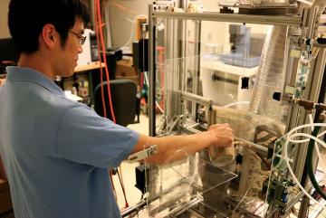 Kevin Kung, a Tata Fellow and PhD candidate in biological engineering, feeds rice husks into the torrefaction reactor in his lab at MIT. A thermochemical process will convert the biomass to a more energy-dense form, making it easier to transport an...