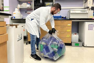
              Normand Desrochers, MIT EHS technician, picks up pipette tip boxes and conical tube racks to be recycled. 
              Photo: Hao Nguyen
      