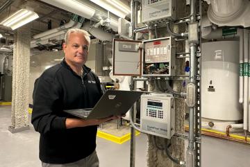 Fran Selvaggio, senior building management systems engineer in the MIT Department of Facilities, stands in the newly renovated Met Warehouse, where an innovative heat-recovery system captures heat rejected from the campus cooling system and uses electric heat pumps to generate heat for the building. 