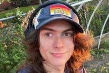 Headshot of Dylan with headphones in a garden